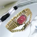 Close-up of red oval dial gold watch with rhinestone bezel and metal strap details. - Gold Red