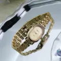 Close-up detail shot of a vintage oval gold quartz wristwatch with sparkling rhinestone bezel. - Gold