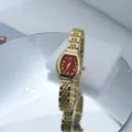 Close-up van het luxe gouden quartz horloge met rode tonneau wijzerplaat en metalen armbandbandje. - Goud Rood