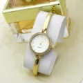 Women fashion quartz bracelet watch with rhinestone bezel and gold metal strap detail. - White
