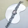 Detailansicht der unregelmäßigen Metall-Quarzuhr mit Zifferblatt und markantem Gliederarmband. - Silberrosa