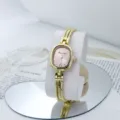 Reloj de cuarzo dorado para mujer con esfera ovalada rosa y pulsera de cadena multi hilos. - Rosa