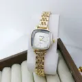 Gros plan détaillé d'une petite montre à quartz dorée carrée pour femme avec bracelet métallique. - Or Blanc