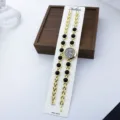 Goldene Quarz Armbanduhr Detailansicht, elegantes Metallkettchen mit schwarzen runden Perlen. - Schwarz