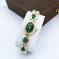 Detail view of a luxury women quartz watch featuring green oval dial and golden chain strap. - Green