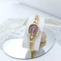 Exquisito detalle del pequeño reloj de cuarzo dorado con una fina correa de cadena. - Rojo