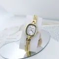 Elegante reloj de cuarzo dorado con delicada esfera ovalada y correa de múltiples hilos para mujer. - Blanco