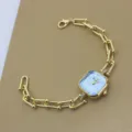 Detailaufnahme einer vergoldeten Quarzuhr mit blauem Zifferblatt und Gliederarmband. - Seeblau