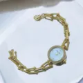 Nahaufnahme einer goldenen Quarzuhr mit Strasslünette, blauem Zifferblatt und Kette. - Himmelblau
