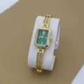 Detailed shot of gold bracelet watch with green rectangular dial and elegant metallic cuff. - Green