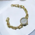 Nahaufnahme der goldenen Quarzuhr mit Strasslünette und strukturiertem Kettenarmband. - Grau