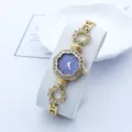 Elegante Damen Quarz Armbanduhr mit blauem Zifferblatt, Blumenlünette und Strasssteinen. - Gold Blau