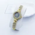 Detailaufnahme einer Damen Quarzarmbanduhr mit Strass Lünette und goldenem Gliederarmband. - Goldschwarz