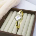 Elegant clover quartz wristwatch featuring dazzling rhinestone bezel and gold finish bracelet design. - Rhinestone Style / Gold White