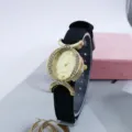 Detalle en primer plano de reloj de mujer con esfera ovalada de estrás y correa de nailon. - Negro