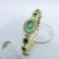 Detailansicht der goldenen Oval-Quarzuhr mit grünem Zifferblatt, Strasssteinen und Kette. - Gold Grün
