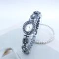 Nahaufnahme einer Damen Quarzarmbanduhr mit Strasssteinen, ovalem Zifferblatt und Gliederarmband. - Silber Weiß