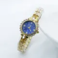 Detail view of a golden women quartz watch with blue rhinestone dial and shimmering crystal bezel. - Gold Blue