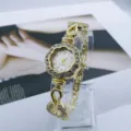 Vista detallada del elegante reloj de cuarzo para mujer con flores doradas y brillantes. - Blanco