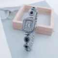 Close-up detail of luxury women rhinestone quartz watch with square dial and teardrop gems. - Black