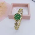 Detail van het quartz horloge met groene wijzerplaat en gouden bandje met strass klaver details. - Goud Groen