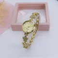 Goudkleurige klaver kwartshorloge detailopname met schitterende strass-steentjes en armband. - Helemaal Goud