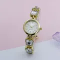 Detailed close-up shot showcasing the sparkling rhinestone butterfly bracelet quartz watch dial. - Gold White