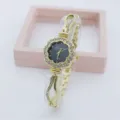 Detailed close-up view of the rhinestone flower dial quartz women watch with gold metal band. - Gold Black