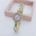 Detail view of the elegant rhinestone flower quartz watch with a pink dial and gold chain strap. - Gold Purple