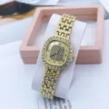 Close-up detail of the elegant square rhinestone gold quartz watch with shiny crystal bezel. - Gold Gold