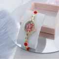 Elegante reloj de cuarzo para mujer con esfera ovalada roja, pulsera dorada y cristales brillantes. - Rojo