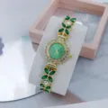 Detailopname van een dames quartz horloge met groene blad edelstenen en kristallen wijzerplaat. - Goud Groen
