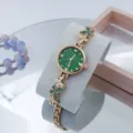 Detailweergave van dames kwartshorloge met groene wijzerplaat en vlinder kristallen armband. - Roségoud Groen