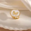 Dettaglio ravvicinato dell'anello in acciaio inossidabile dorato con smalto bianco e farfalla. - Stile Farfalla in Rilievo Bianco (1852)