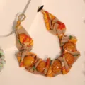 Detailed close-up of bohemian floral print fabric necklace with large amber-textured beads - X-895 Yellow