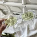 Detailaufnahme von Retro Rechteckige Sonnenbrille mit klarem Rahmen und gelben Gläsern. - Eckige Jelly-Brille mit transparenten weiß-grünen Gläsern