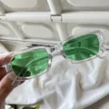 Detailaufnahme trendiger, transparenter Rechtecksonnenbrille mit grünen Gläsern für Streetwear. - Eckige Jelly-Sonnenbrille mit transparentem Rahmen und dunkelgrünen Gläsern
