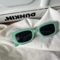 Nahaufnahme der trendigen grünen rechteckigen Sonnenbrille auf weißem Tuch. Modisches Accessoire. - Retro Mintgrüner Rahmen