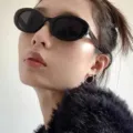 Detailaufnahme der Retro-Ovallsonnenbrille am Modell mit stilvollem schwarzem Rahmen. - Neues Oval Schwarz