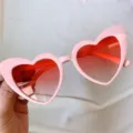 Detailaufnahme der rosa Herz Katzenaugen Sonnenbrille mit roten Farbverlaufsgläsern. - Schräges Herz in komplett Rosa