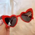 Nahaufnahme von roten Herz-Sonnenbrillen, trendige Mode-Eyewear mit schwarzen Gläsern. - Schräges Herz rot