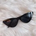 Schwarze Cat-Eye-Sonnenbrille Detailansicht auf weißem Fellhintergrund im Retrostil. - Dreieck komplett Schwarz