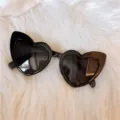 Nahaufnahme von trendigen schwarzen herzförmigen Katzenaugen-Sonnenbrillen auf Pelz. - Schräges Herz - Schwarz