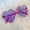 Nahaufnahme von trendigen herzförmigen Sonnenbrillen mit lila Gläsern und rosa Gestell. - Großes Herz Lila