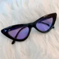 Schwarze Cat-Eye-Sonnenbrille mit lila Gläsern Detailansicht, Retro-Punk-Sonnenbrille nahaufnahme. - Dreieck - schwarzer Rahmen & lila Gläser