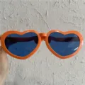 Nahaufnahme von übergroßen herzförmigen Sonnenbrillen mit orangefarbenem Rahmen und blauen Gläsern. - Riesiges Herz / Orange