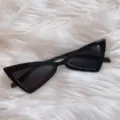 Detailaufnahme von schwarzen Vintage-Dreiecks-Cat-Eye-Sonnenbrillen auf flauschigem Kunstpelz. - Umgedrehtes Dreieck komplett Schwarz