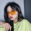 Close-up detail shot of trendy oversized square sunglasses with orange lenses worn by a model. - Dark Yellow