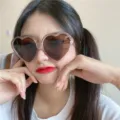Nahaufnahme einer retro rosa herzförmigen Sonnenbrille mit braunen Gläsern für Damen. - Champagner