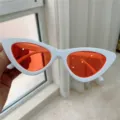 Retro Katzenauge Sonnenbrille mit weißem Gestell und auffälligen orangefarbenen Gläsern. - Weißes Gestell mit roten Gläsern
